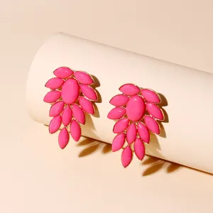 Close-up of vibrant pink acrylic leaf cluster earrings with gold-toned trim for stylish look.