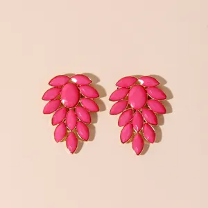 Close-up detail view of vibrant pink cluster leaf statement earrings with polished gold-tone setting.