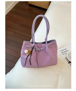 Lavender purple woven leather tote bag with double handles and stylish charm detail.