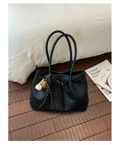 Black woven tote bag detail showing premium leather texture, dual handles and stylish knot.