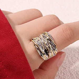 Gros plan d'une large bague géométrique en métal avec texture or et argent, détail élégant.