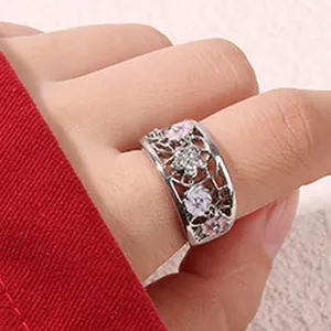 Gros plan détaillé de la large bague florale ajourée avec émail rose et cristaux.