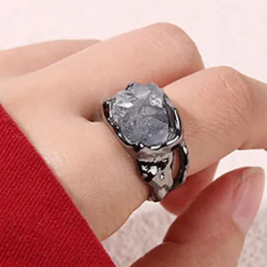Vue rapprochée d'une bague géométrique gothique chic en métal foncé avec de la pierre texturée.
