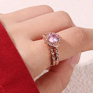 Vue détaillée d'une bague empilable en or rose avec une pierre centrale rose et des zircons clairs.
