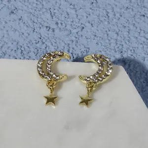 Detail view of crystal-paved crescent moon and hanging star stud earrings in gold tone.