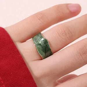 Gros plan détaillé de la large bague émaillée verte irrégulière, montrant une texture métallique.
