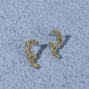 Detail view of elegant gold rhinestone moon and star stud earrings sparkling nicely.