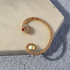 Close-up detail of the gold snake ear cuff featuring sparkling rhinestones and iridescent stone.