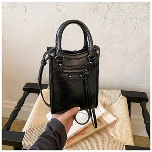 Closeup view of stylish black leather mini tote bag showcasing detailed studs and zipper.