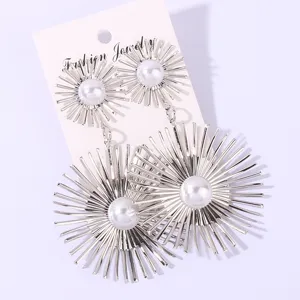 Detailed close-up view of long silver starburst pearl earrings showing exquisite metal ray design.