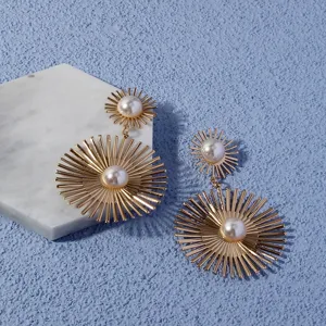 Detail view of trendy golden sunburst pearl drop earrings, elegant fashion jewelry for women.