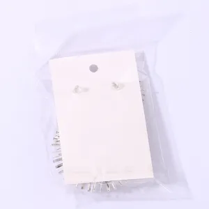 Detailed view of metal fringe starburst earrings on display card in clear plastic packaging bag.