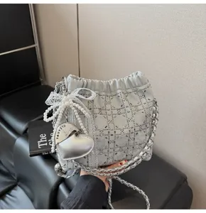 Silver chain bucket bag with pearl bow and heart pendant, elegant fashion detail view.