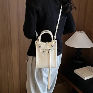 Detail view of the stylish white mini vertical crossbody bag with front tassel pocket.