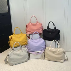 Primer plano detallado de bolsos de viaje multicolores con cuerpo de nylon y asas de cuero.