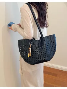 Close-up detail of the stylish black woven leather shoulder tote bag showing exquisite texture.