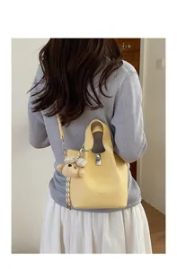 Vista dettagliata della borsa a secchiello gialla elegante con serratura e ciondolo.