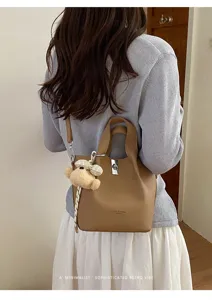 Borsa a secchiello in pelle chic con ciondolo a orsetto e manico per donne eleganti tutti i giorni.