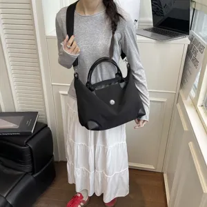 Gran bolsa de viaje negra de nylon con asas de cuero y correa de hombro práctica.