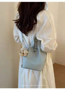 Vista dettagliata dell'elegante borsa a secchiello azzurro con ciondolo orsetto e serratura.