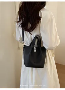 Dettaglio della borsa a secchiello minimalista in pelle nera con chiusura a gancio.