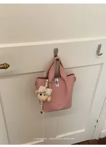 Vista dettagliata di una borsa a secchiello rosa con ciondolo orsetto e chiusura retrò.