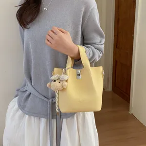 Borsa secchiello gialla elegante da donna con ciondolo orsetto, borsa a tracolla alla moda.