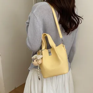 Borsa a secchiello in pelle gialla da donna, elegante borsa a tracolla con ciondolo orsetto.