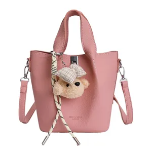 Elegante borsa a secchiello in pelle rosa con ciondolo orsetto, manico e tracolla per donna.