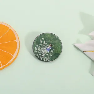 Gros plan détaillé du badge rond en métal avec illustration de fille anime dans les fleurs.
