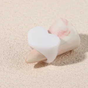 Close-up detail of a minimalist white heart acrylic ring, showing smooth resin surface and finish.