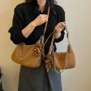 Schicke braune geflochtene Hobo-Umhängetasche Detail mit Metallkette und süßem Bärchen-Anhänger.