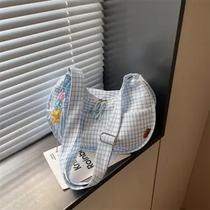 Dettaglio borsa a tracolla a quadretti blu e bianca, borsa casual con ciondoli a stella carini.