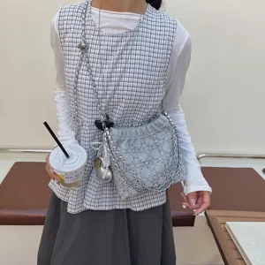 Close-up detail shot of a stylish women chain bucket shoulder bag worn with casual outfit.