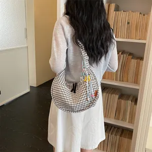Vista dettagliata della borsa a tracolla casual a quadri bianchi e neri con pendenti.