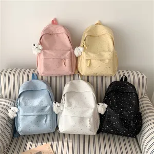 Vue détaillée de sacs à dos scolaires en toile avec imprimé étoiles et pendentifs ours en peluche.