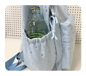 Gros plan sur la poche latérale du sac à dos bleu clair avec étoiles argentées et bouteille.