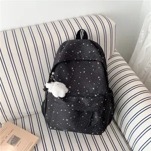 Vue détaillée du sac à dos noir avec imprimé étoiles et charm duveteux sur le canapé.