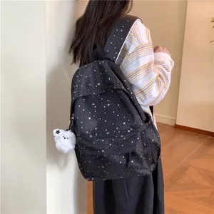 Vue détaillée d'un sac à dos noir imprimé d'étoiles avec pendentif peluche mignon