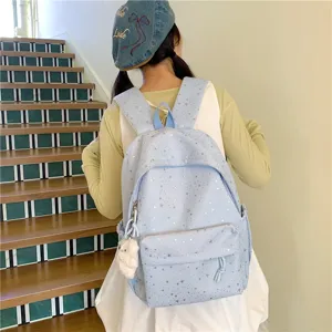 Vue détaillée du sac à dos bleu clair avec étoiles, poche avant et charm en peluche.