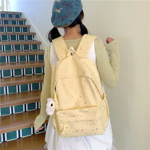 Vue détaillée du sac à dos en toile jaune à motif d'étoiles et joli pendentif peluche.