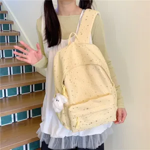 Gros plan détaillé du joli sac à dos jaune clair imprimé d'étoiles avec un pendentif en peluche.