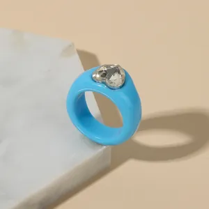 Close-up detail shot of a stylish blue resin heart ring with a sparkling crystal stone.