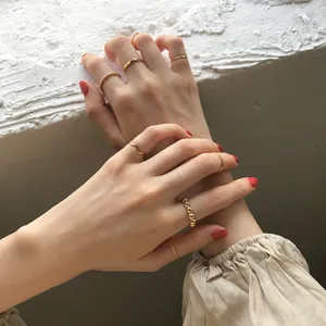 Gros plan d'un ensemble de bagues empilables dorées minimalistes aux motifs perlés et lisses.