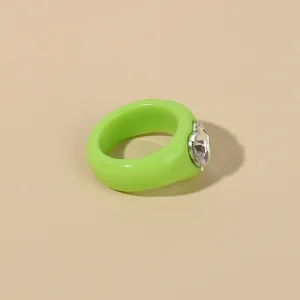 Close-up detail shot of a stylish green acrylic resin ring featuring a sparkly heart crystal.