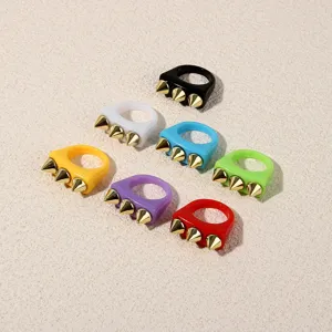 Colorful acrylic rings with gold spikes. Punk style fashion detail shot for trendy daily wear.