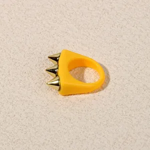 Yellow acrylic spike ring detail, edgy punk fashion finger jewelry close-up shot.