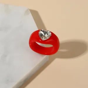 Detail shot of trendy red acrylic chunky ring with heart crystal inlay for women.
