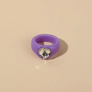 Purple acrylic heart ring detail shot, showing smooth resin band and faceted crystal inlay.