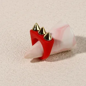Red acrylic ring with gold-tone spikes, punk style statement finger jewelry detail shot